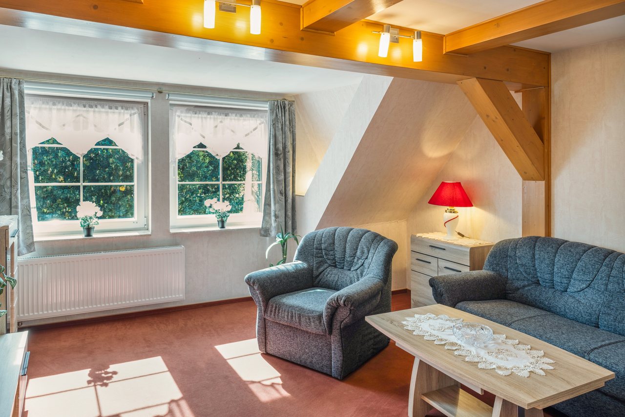 Wohnzimmer mit Sessel und Sofa unter sichtbaren Holzbalken, Ferienwohnung Zwei in Bad Wilsnack, Brandenburg, Bad Wilsnack, Prignitz, Brandenburg