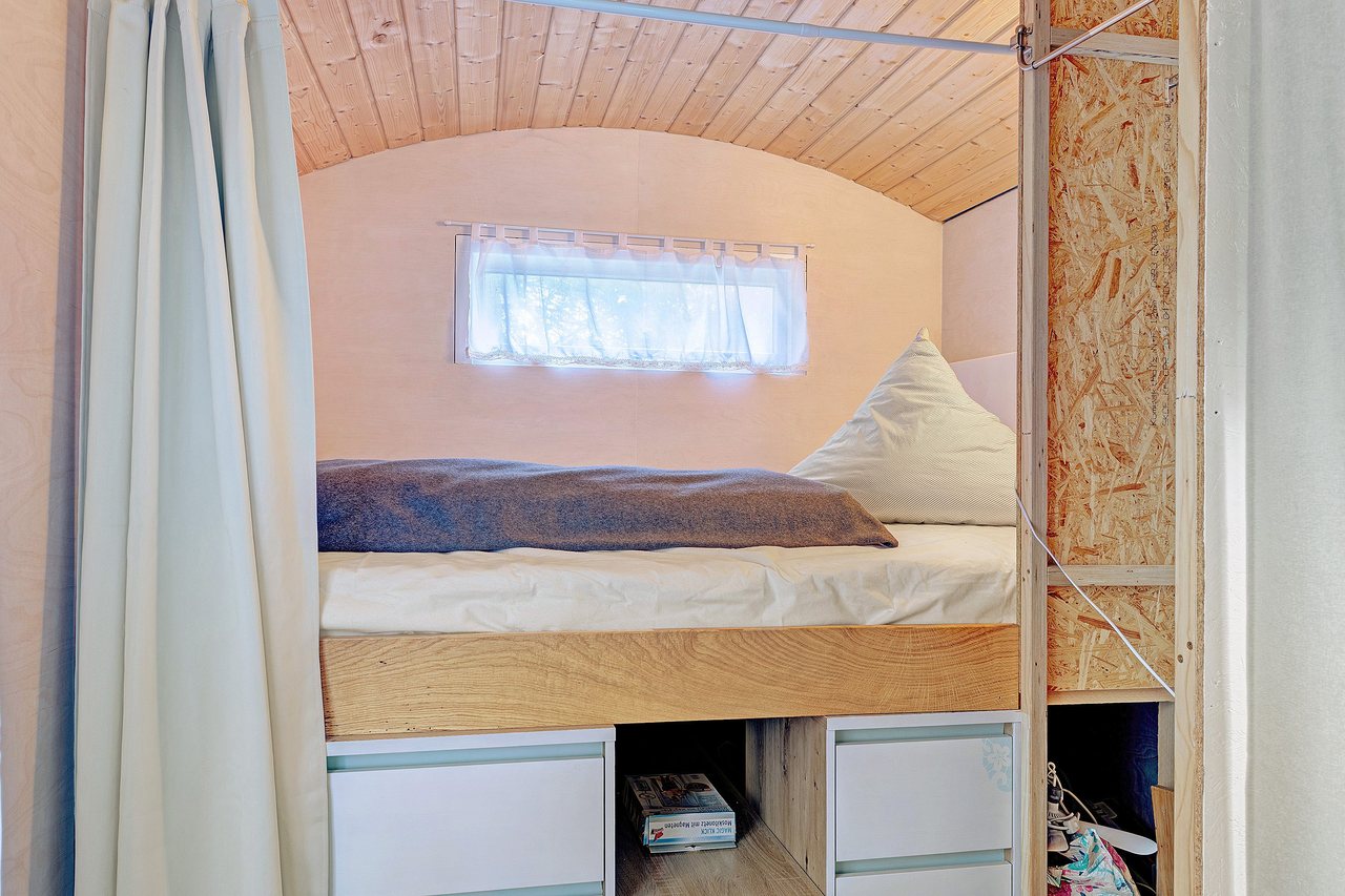 Schlafbereich mit Bett unter der Holzdecke, Bauwagen in Marienfließ, Brandenburg