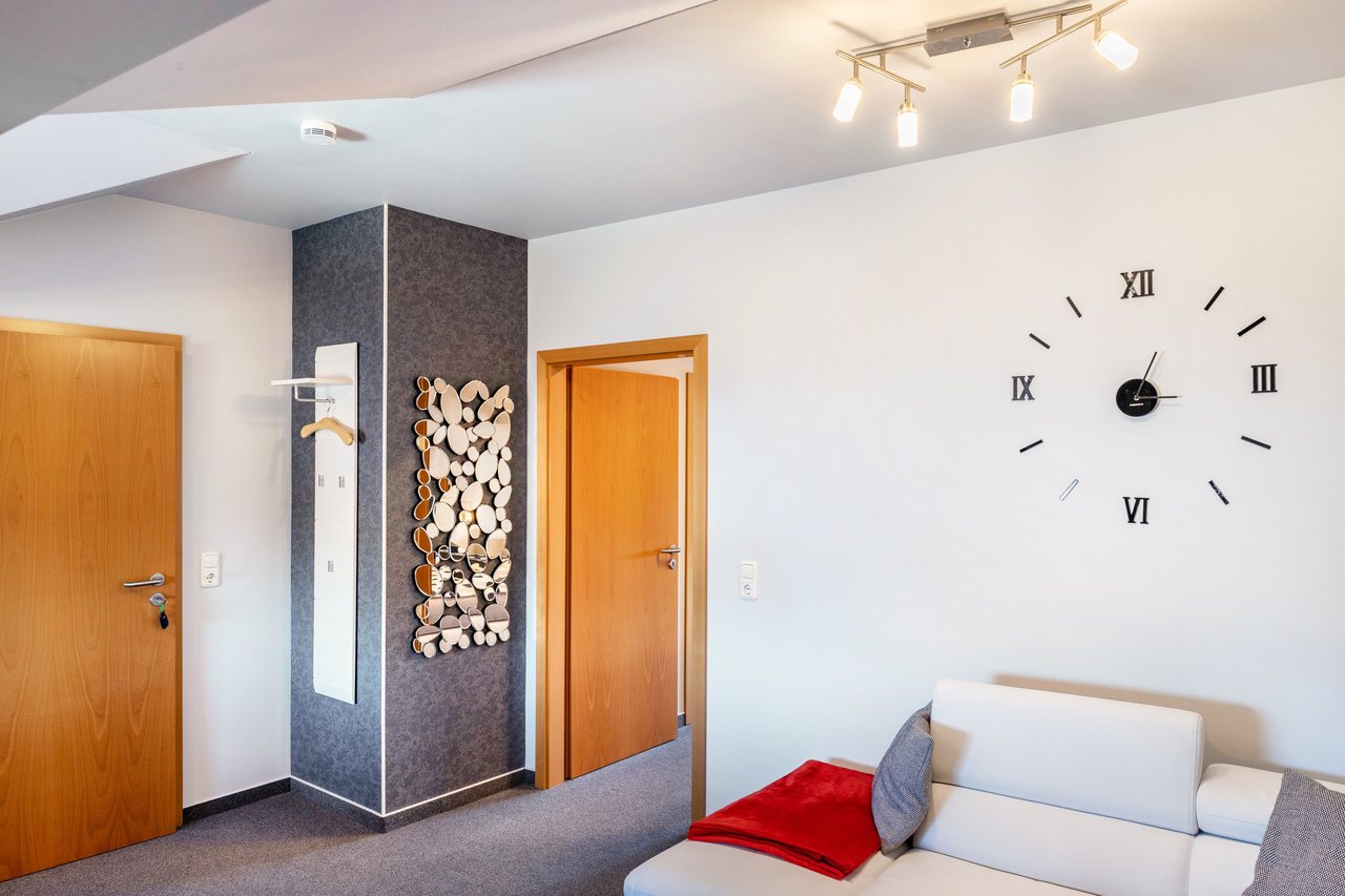 Zimmer mit Sofa und Wanduhr, Apartment über dem Pub in Michendorf, Brandenburg