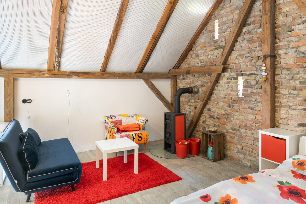 Schlafbereich mit Sofa und Kaminofen unter der Dachschräge, Rotes Haus im Havelland in Werder (Havel), Brandenburg