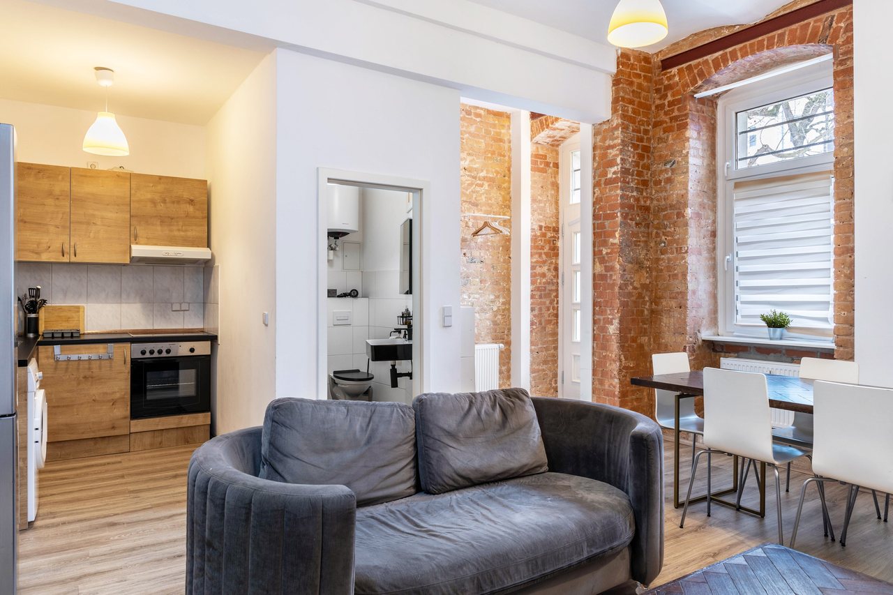 Wohnbereich mit Sofa und Küchenzeile vor Backsteinwand, Backyard Loft West-Berlin in Berlin