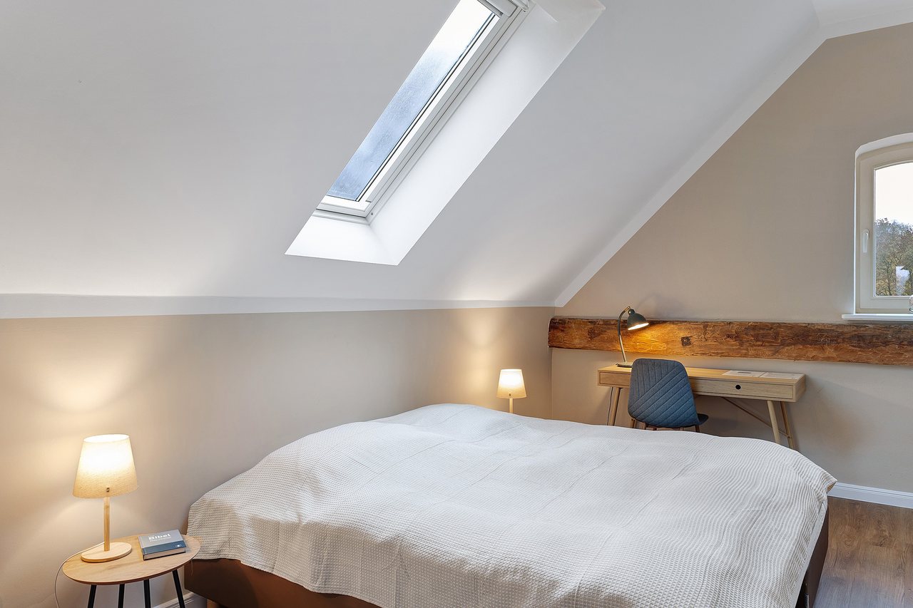 Doppelbett mit Schreibtisch unter der Dachschräge, Doppelzimmer in Marienfließ, Brandenburg