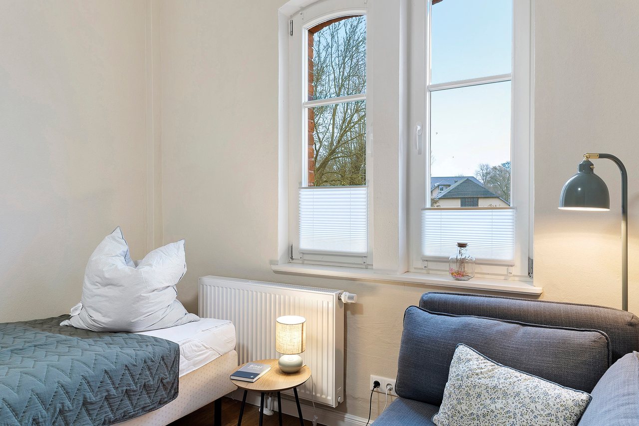 Bett mit Sessel am Fenster, Doppelzimmer in Marienfließ, Brandenburg