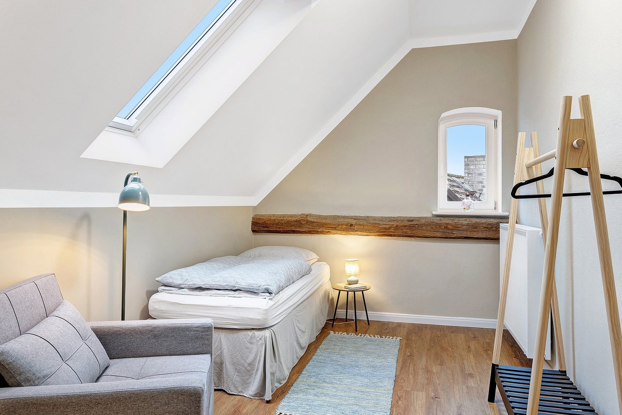 Einzelbett mit Sessel und Kleiderständer unter der Dachschräge, Einzelzimmer in Marienfließ, Brandenburg