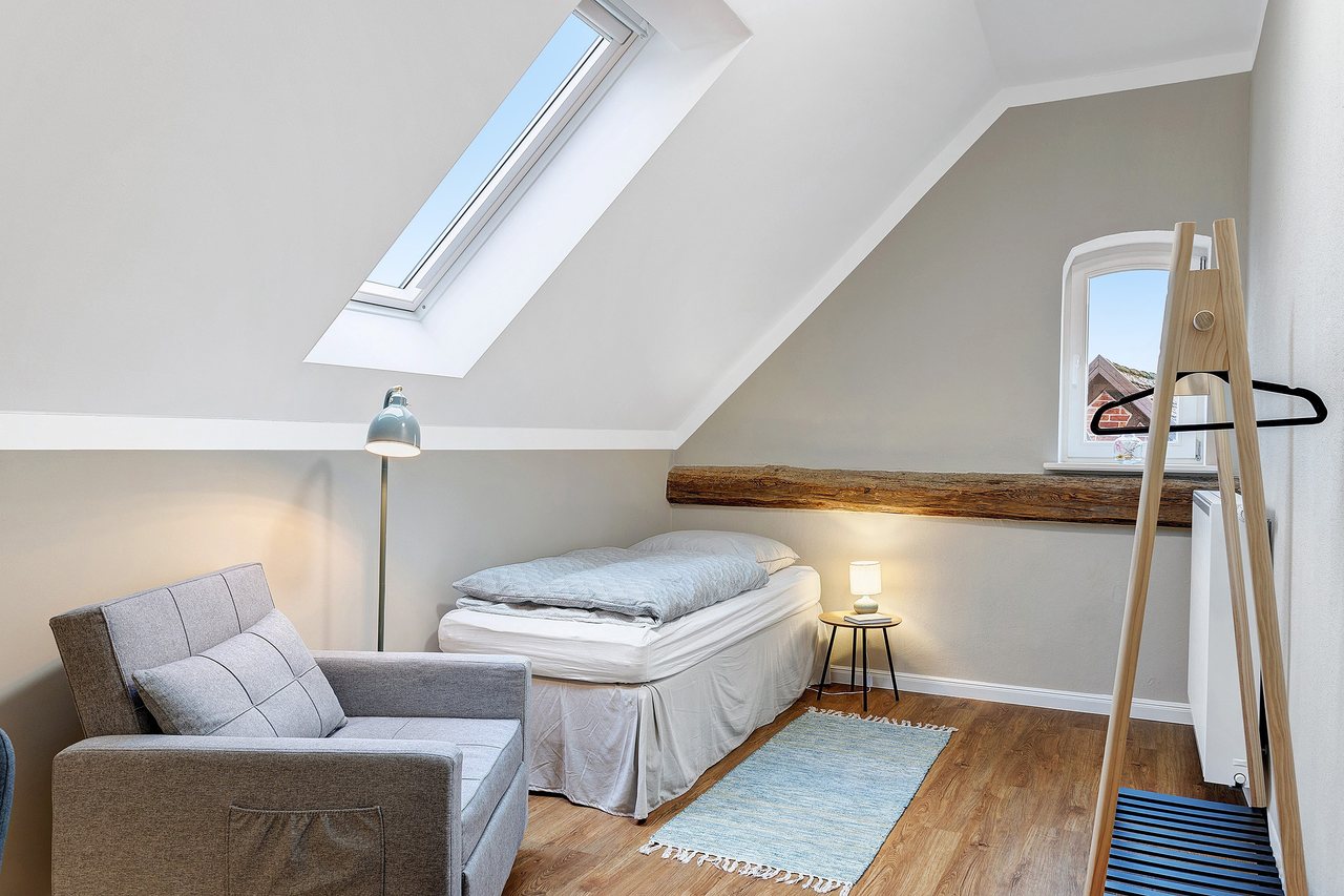Einzelbett mit Sessel unter der Dachschräge, Einzelzimmer in Marienfließ, Brandenburg